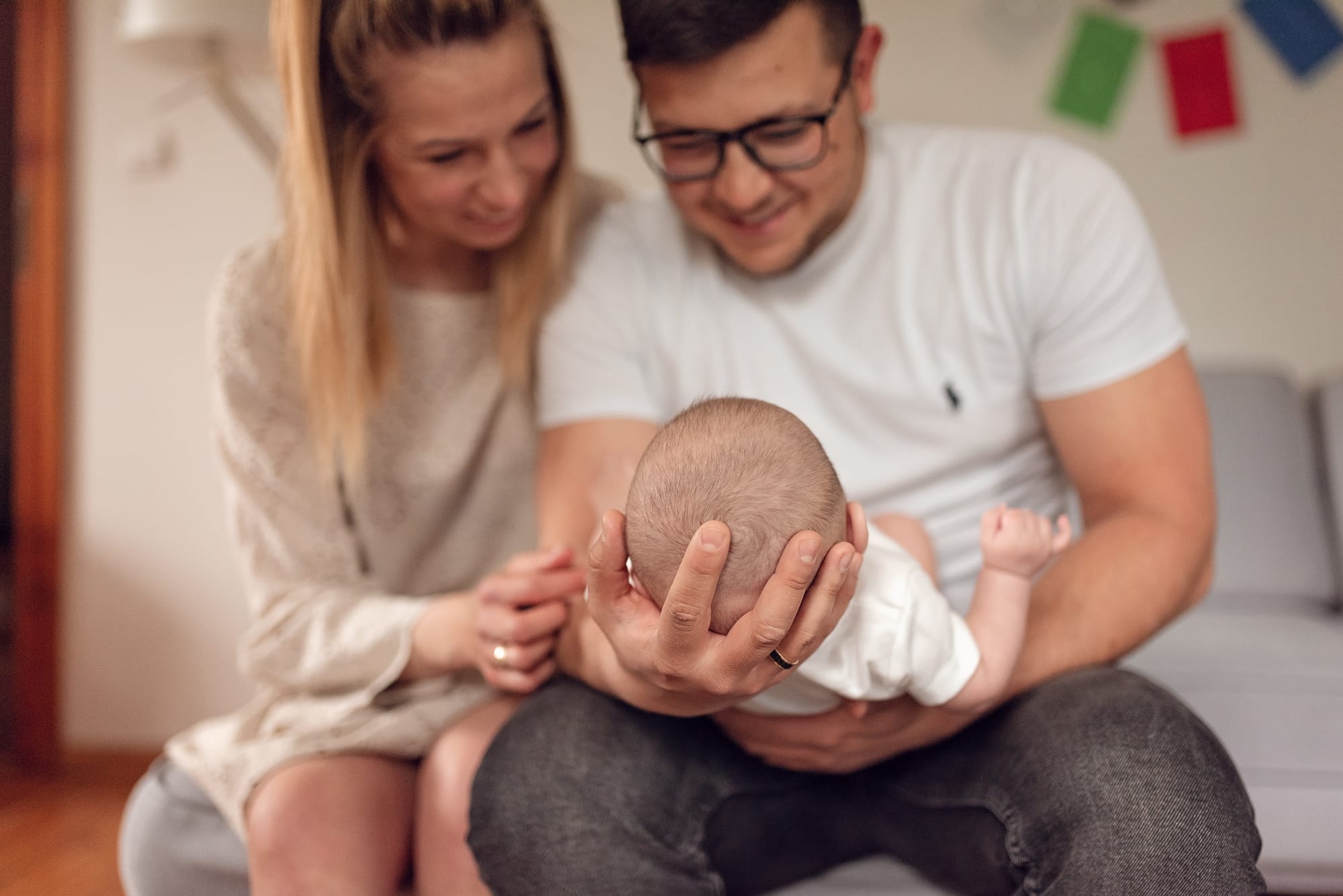 Rodzice patrzą na niemowlę sesja niemowlęca w domu