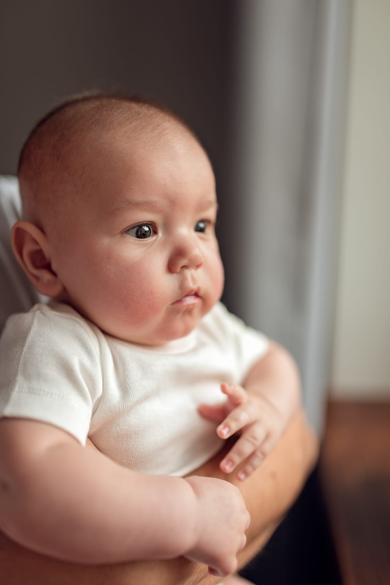 Tata tuli niemowlę przy oknie domowa sesja rodzinna