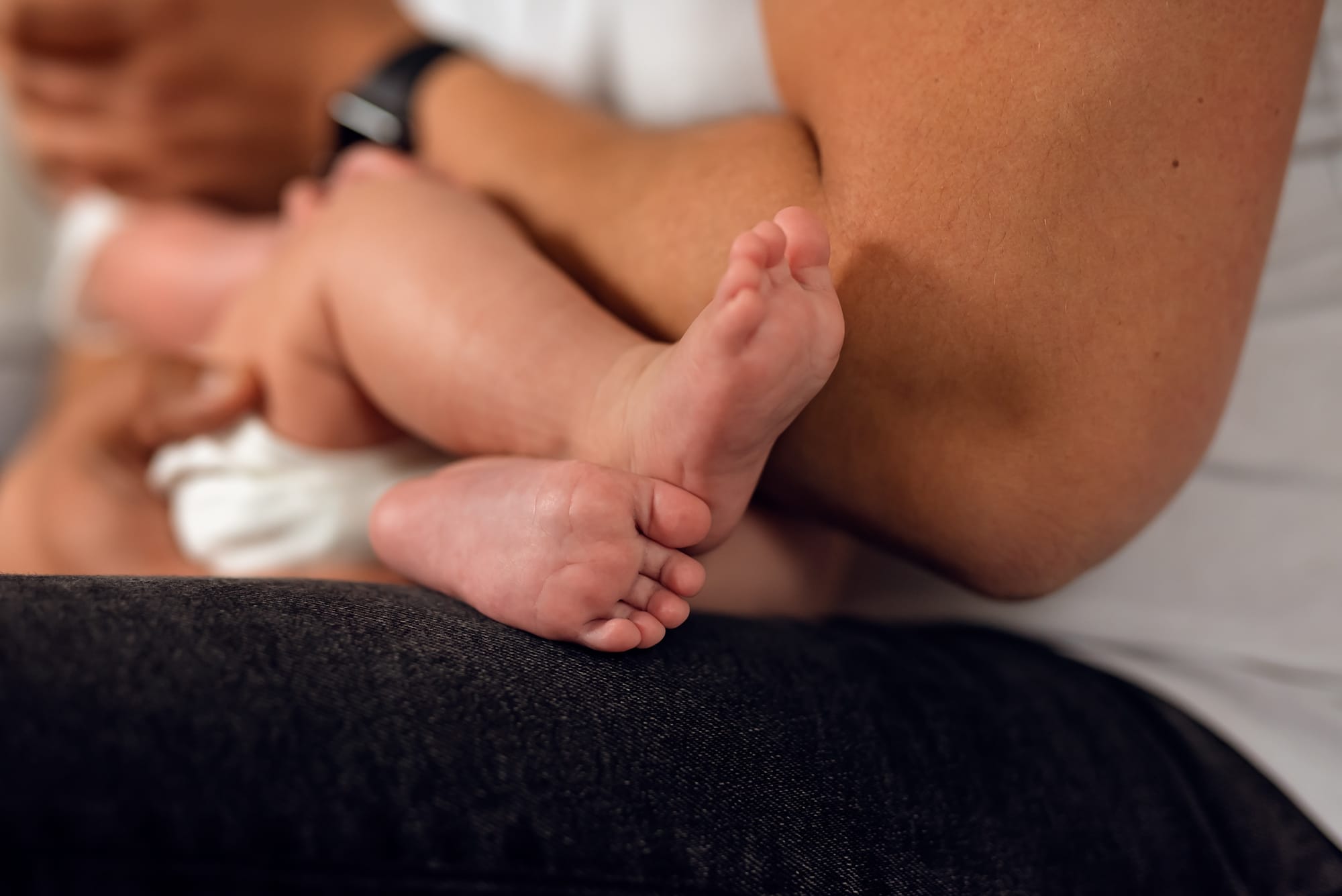 Stópki niemowlęcia w ramionach taty sesja w domu
