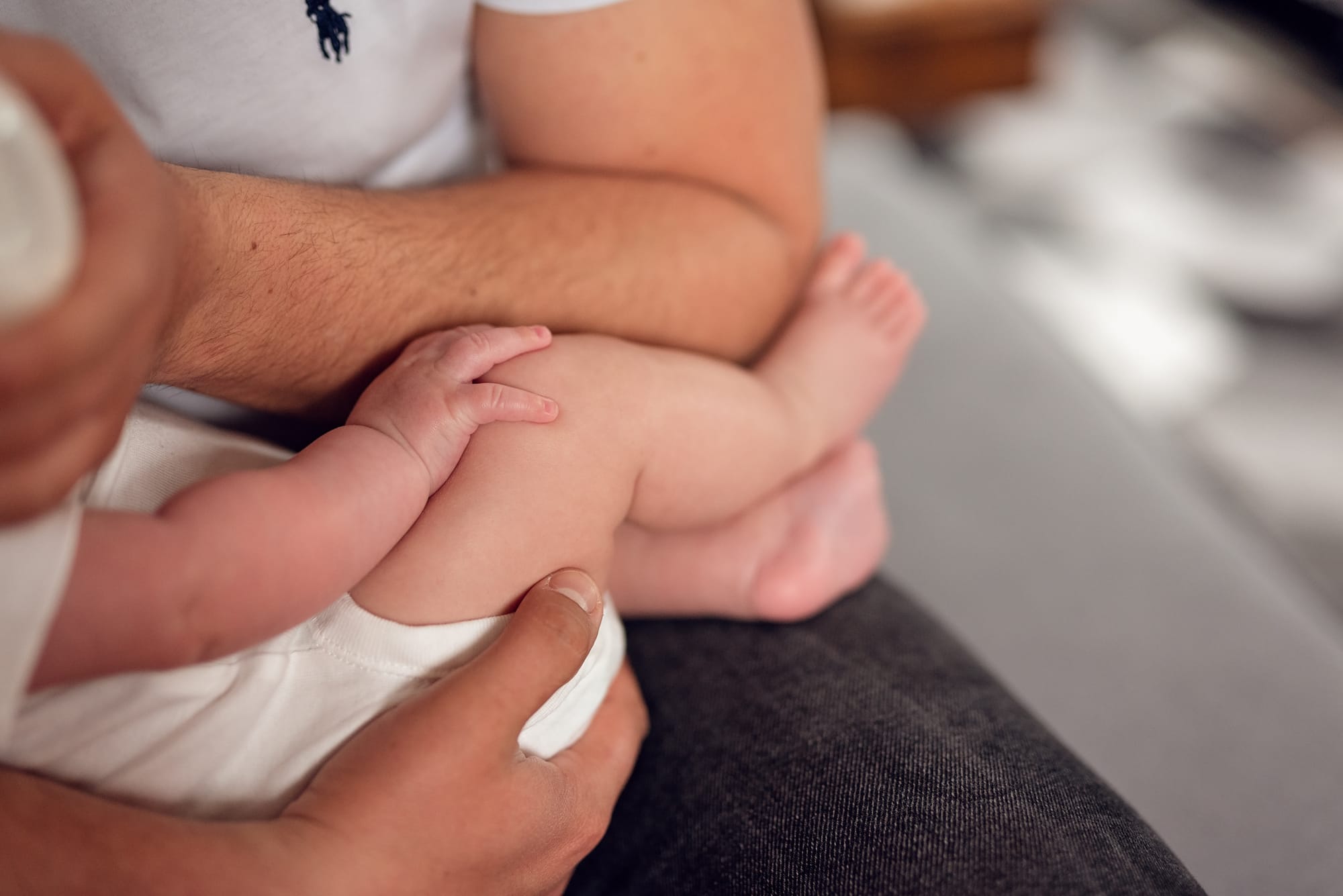 Karmienie butelką niemowlę trzyma dłoń na kolanie sesja w domu