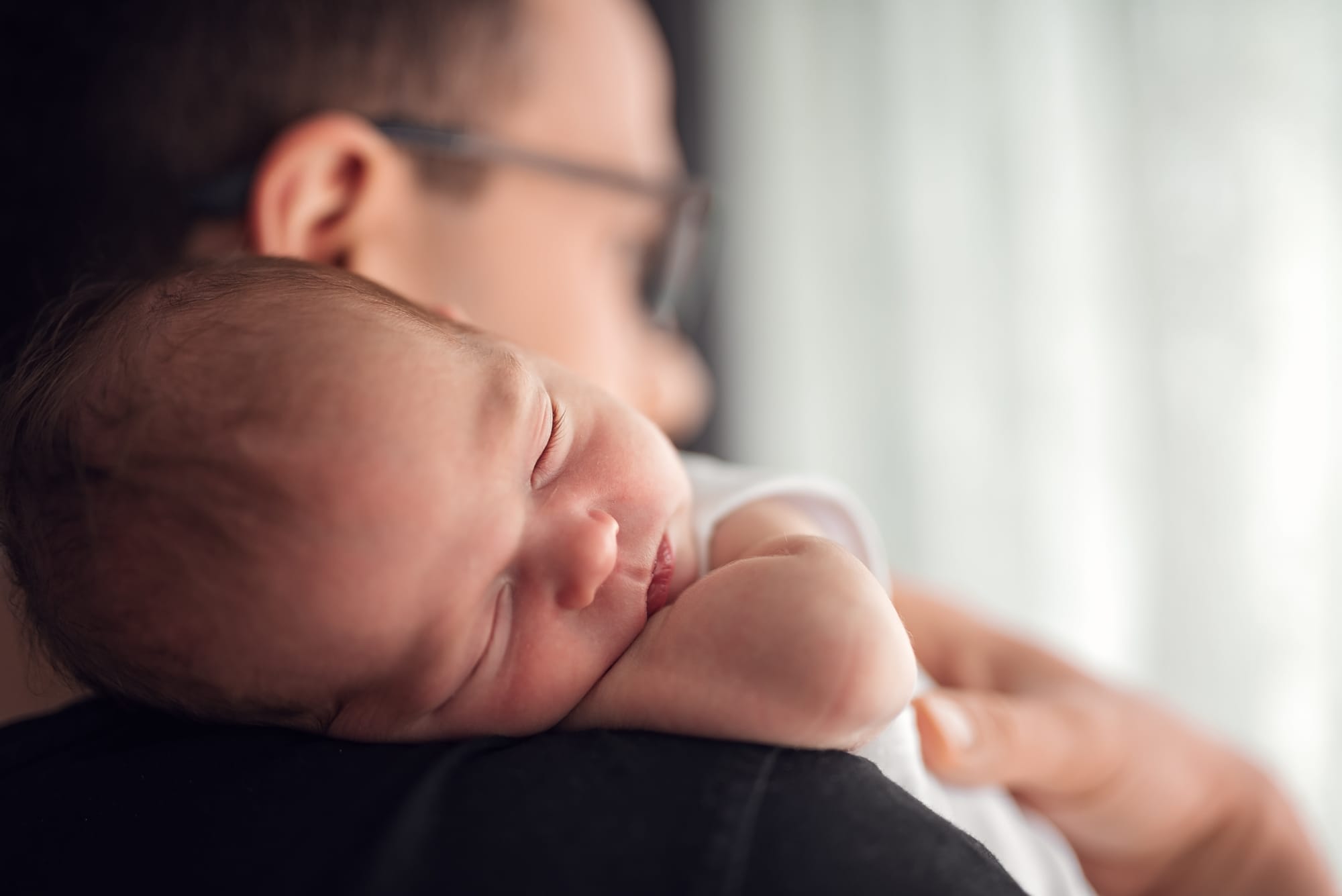 Tata z noworodkiem przy oknie naturalne światło sesja w domu