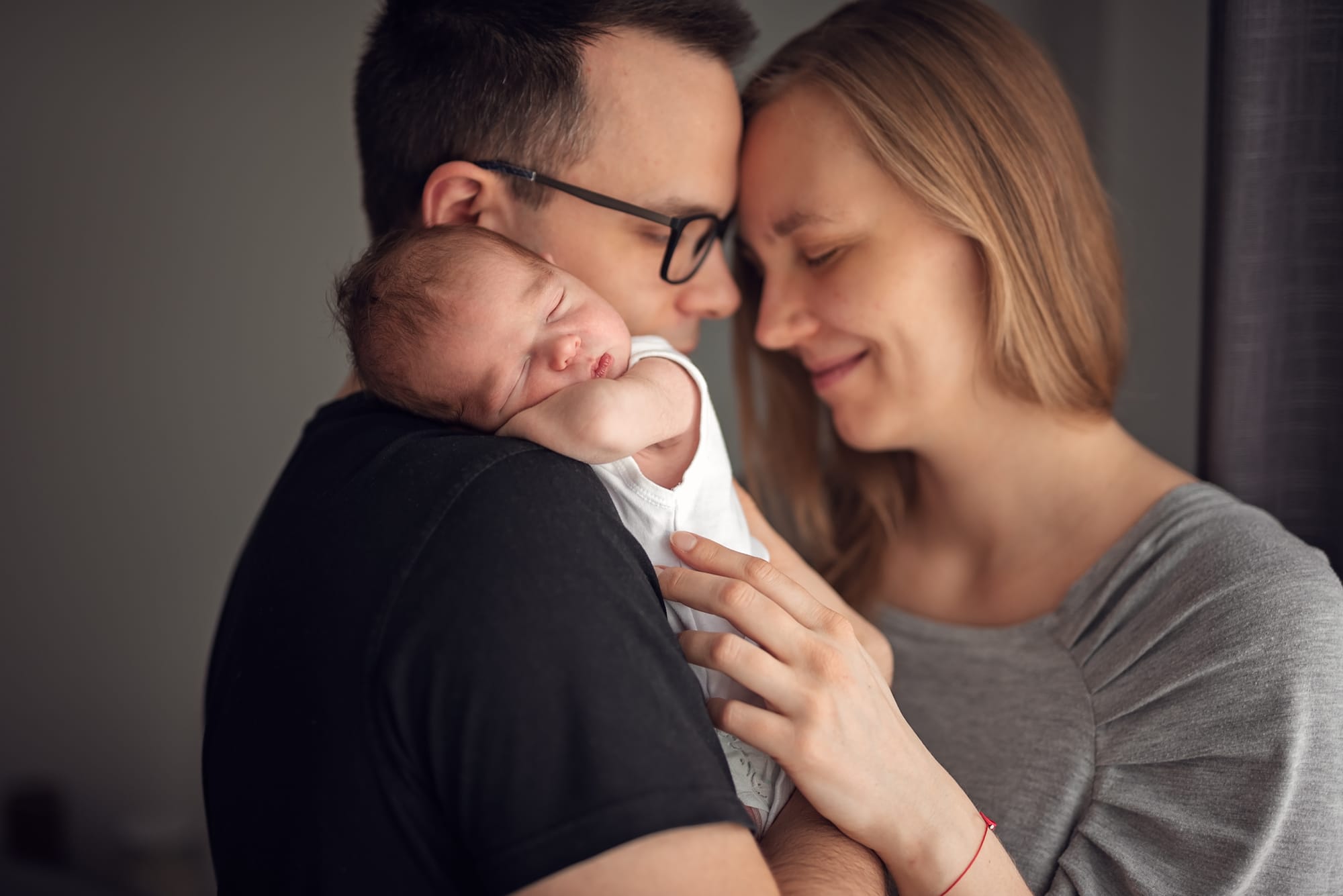 Rodzice z noworodkiem przy oknie jak przygotować dom do sesji