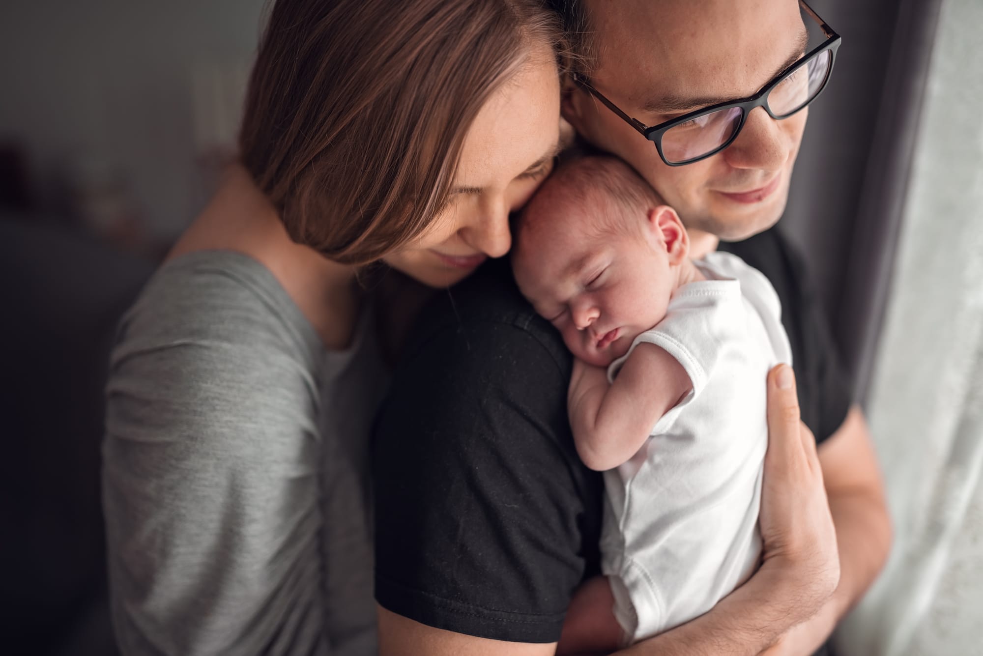 Mama przytula tatę z noworodkiem sesja w domu