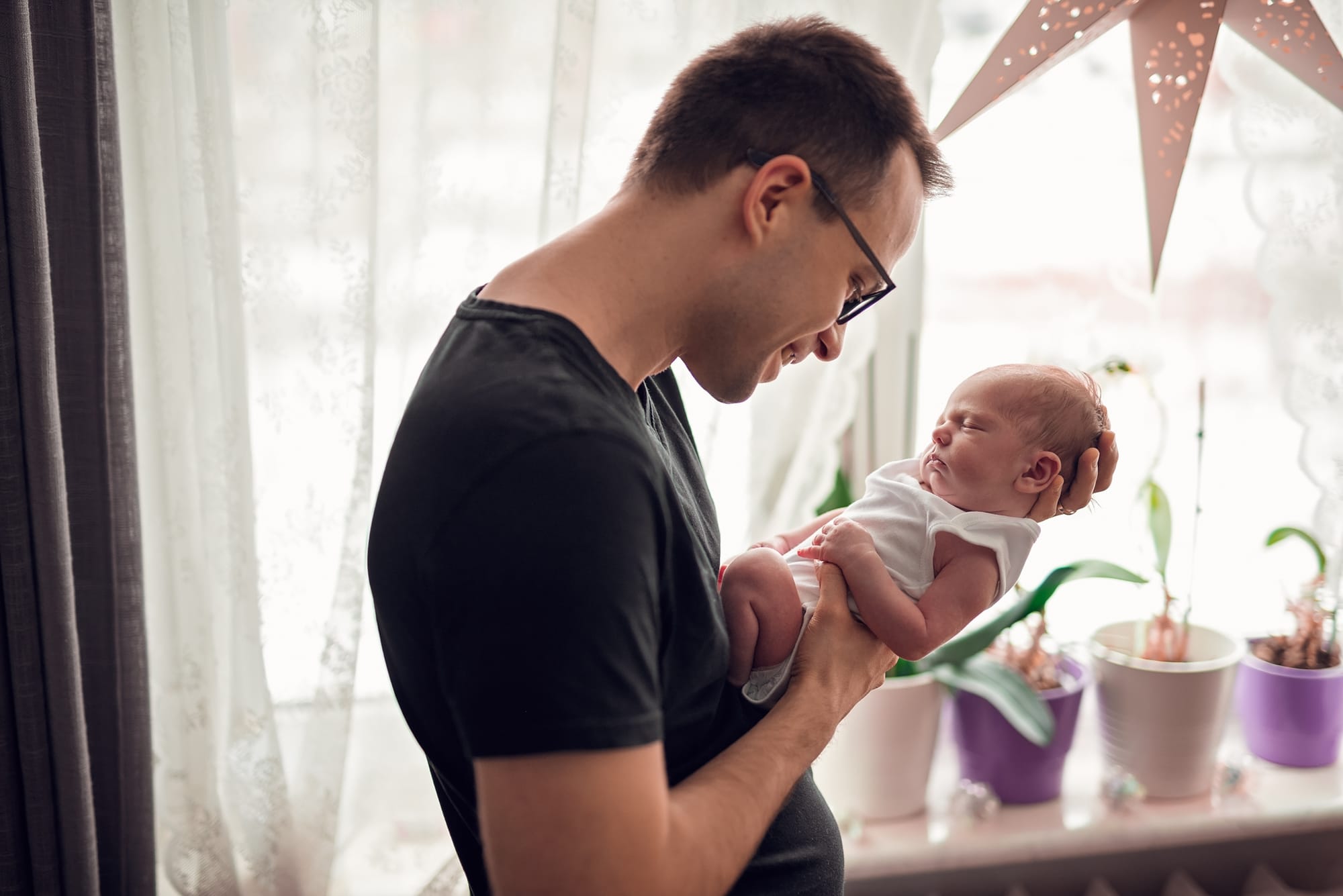 Tata patrzy na noworodka sesja noworodkowa w domu