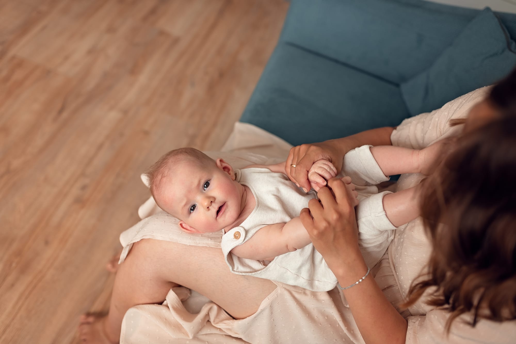 Niemowlę na kolanach mamy w domowym zaciszu sesja Gdańsk
