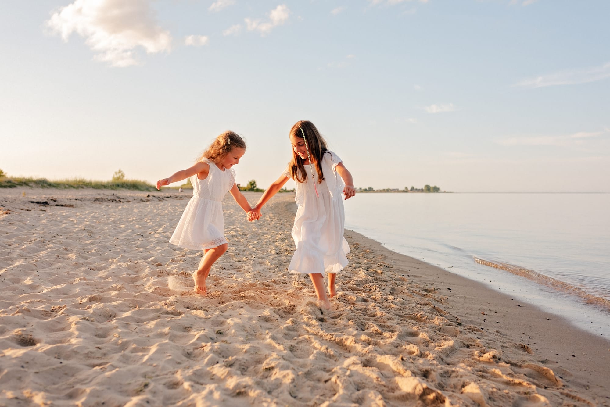 Siostry tańczą na plaży dopasowane kolory sesja rodzinna