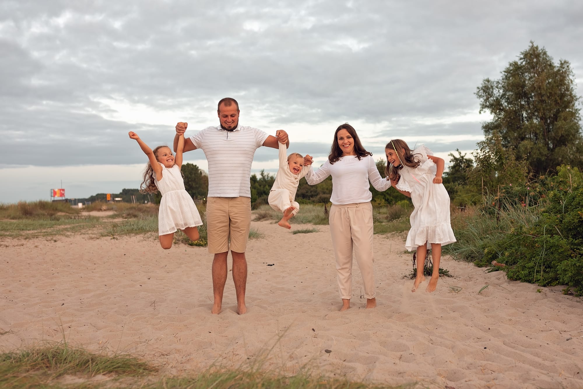Rodzice podrzucają dzieci na plaży sesja rodzinna Gdynia