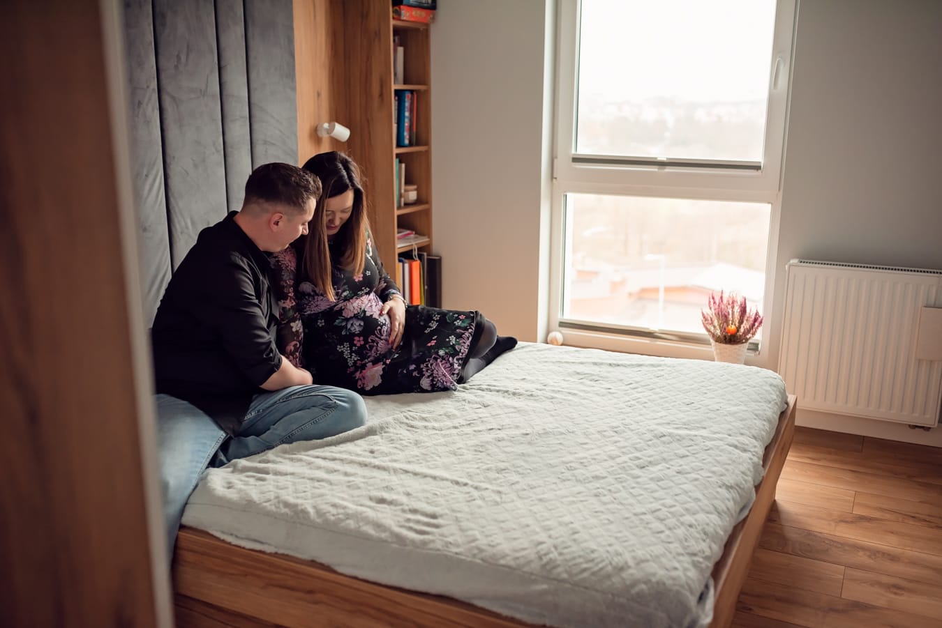 Rodzice patrzą na brzuszek sesja ciążowa w domu