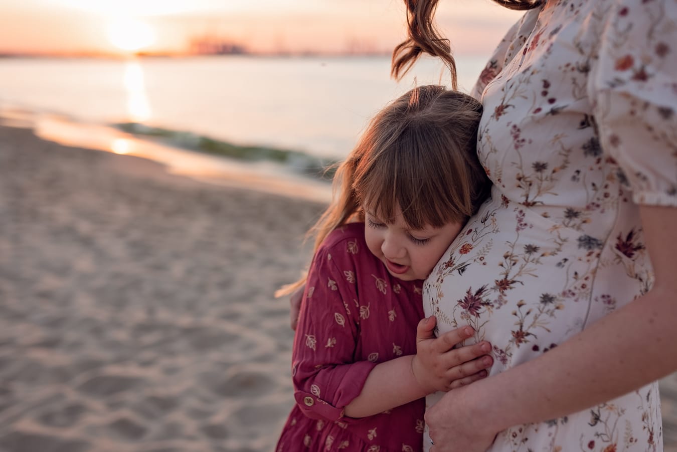 Córka słucha kopnięć w brzuszku mamy sesja ciążowa