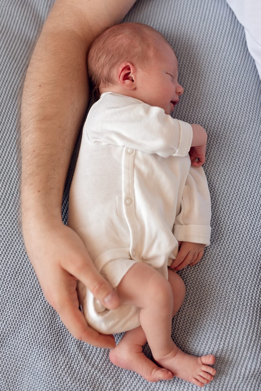Noworodek śpi otulony ręką taty sesja w domu Sopot