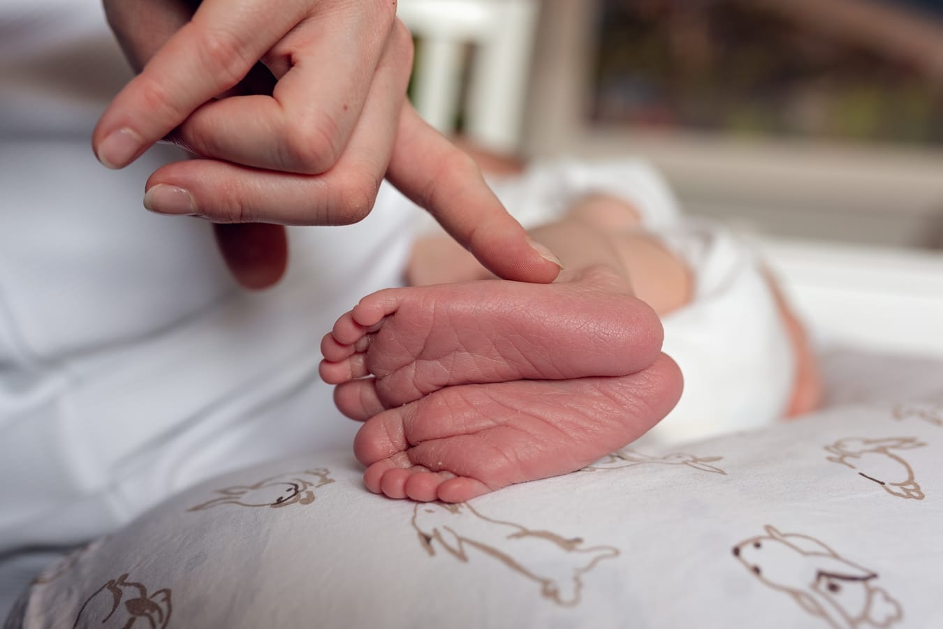 Mama głaszcze noworodka po maleńkich stópkach sesja noworodkowa lifestyle Sopot