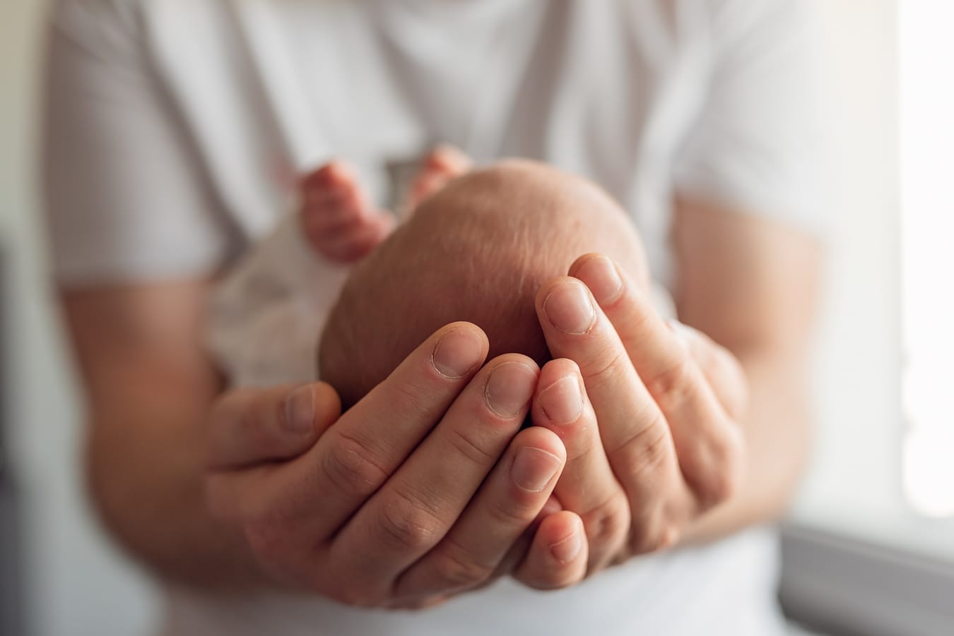 Dłonie taty trzymają noworodka detal sesja Sopot