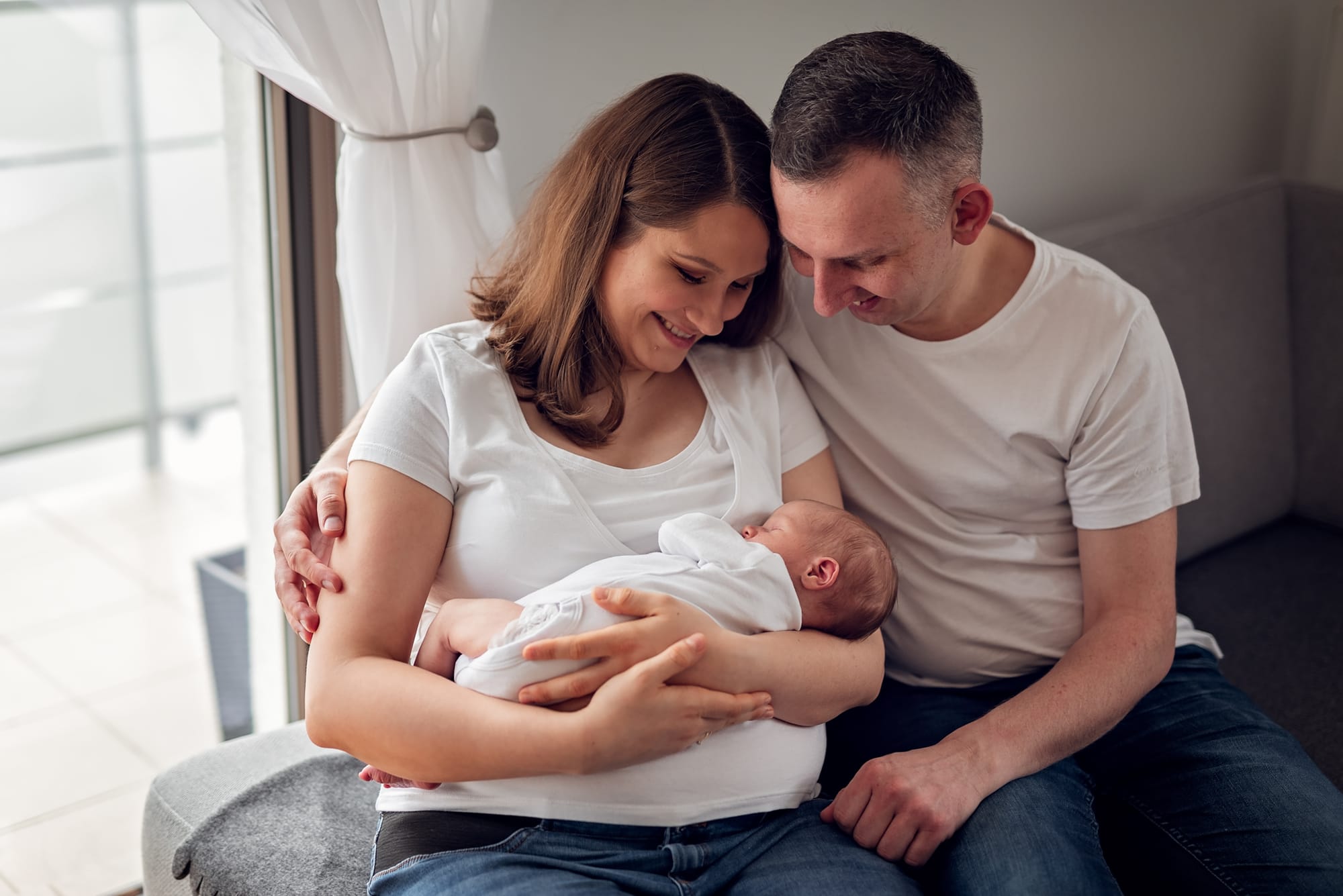 Rodzice z noworodkiem sesja w domu stonowane kolory