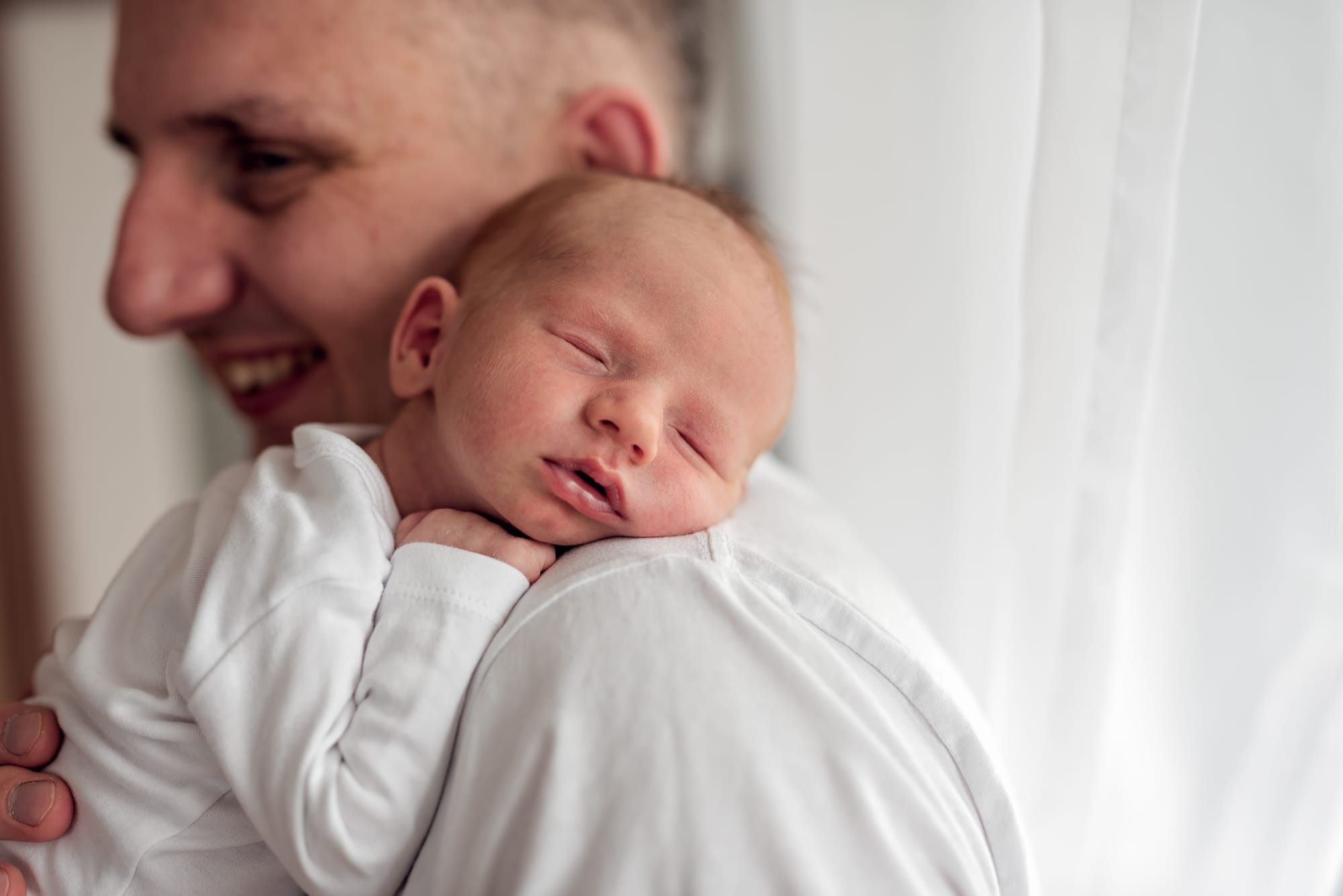 Noworodek śpi na ramieniu taty sesja noworodkowa w domu