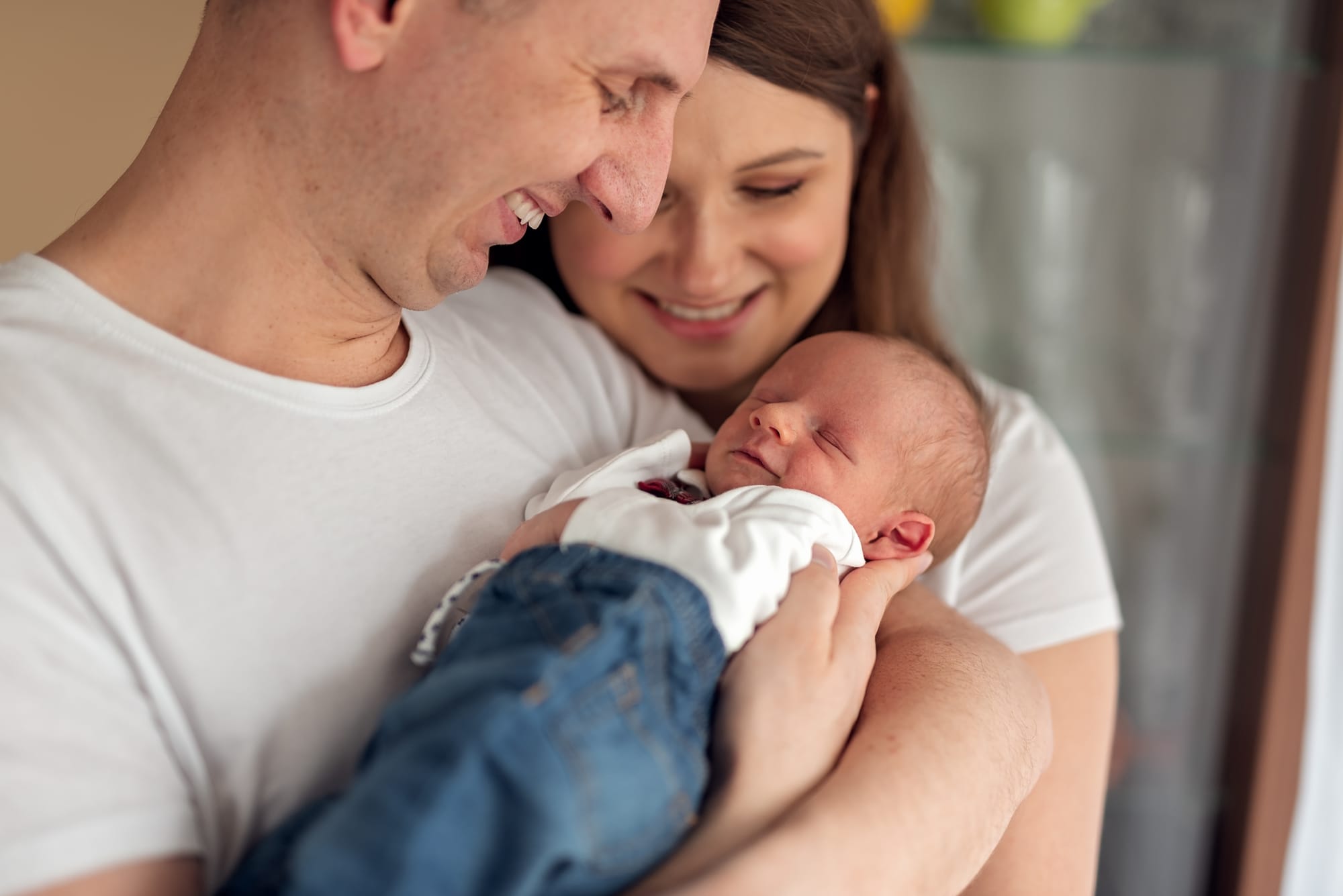 Rodzice z noworodkiem sesja w domu stonowane kolory