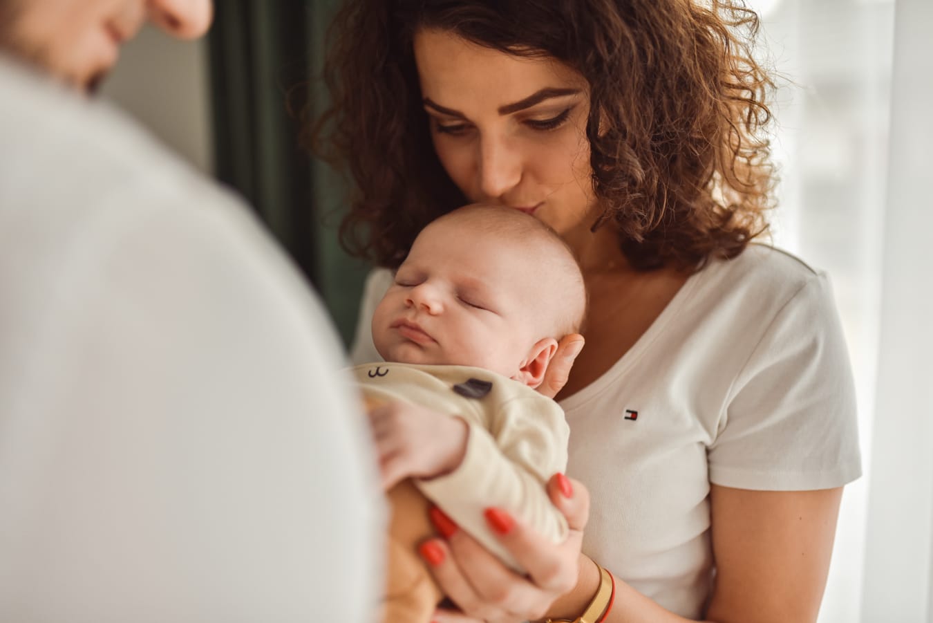 Mama całuje niemowlę na rękach taty sesja w domu