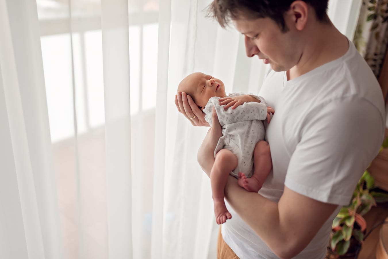 Tata z noworodkiem przy oknie sesja w domu Gdańsk