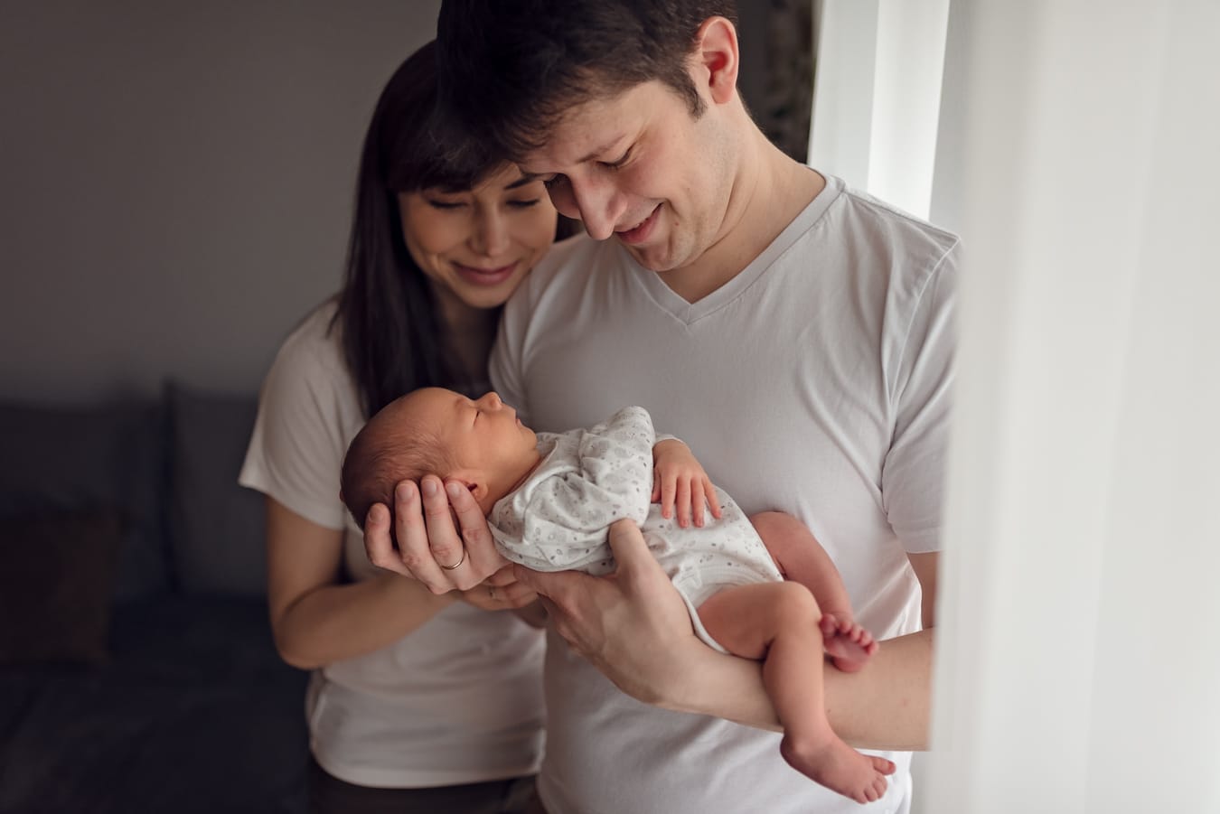 Uśmiechnięci rodzice z noworodkiem sesja w domu Gdańsk