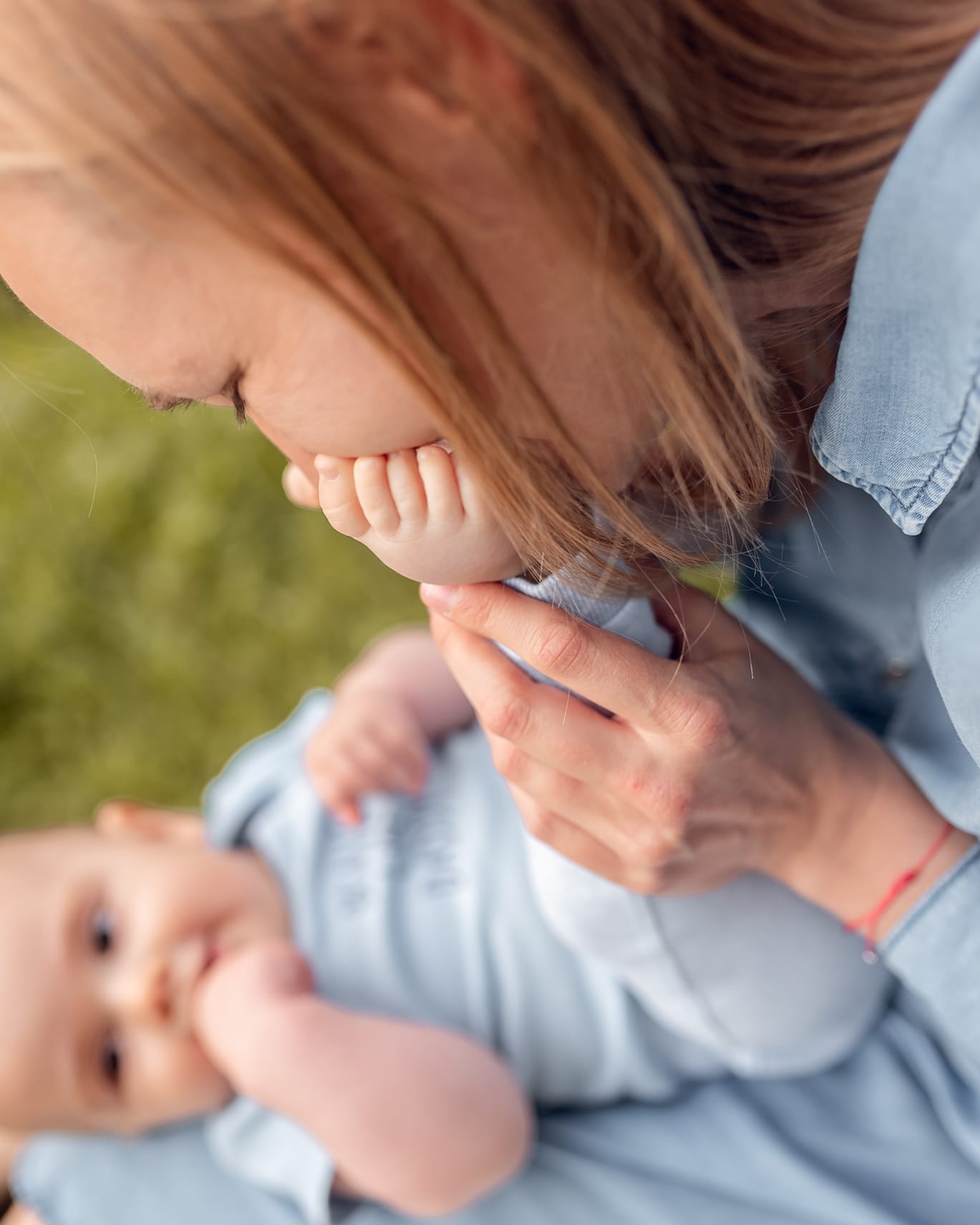 Mama całuje stópki niemowlaka sesja w plenerze Gdańsk