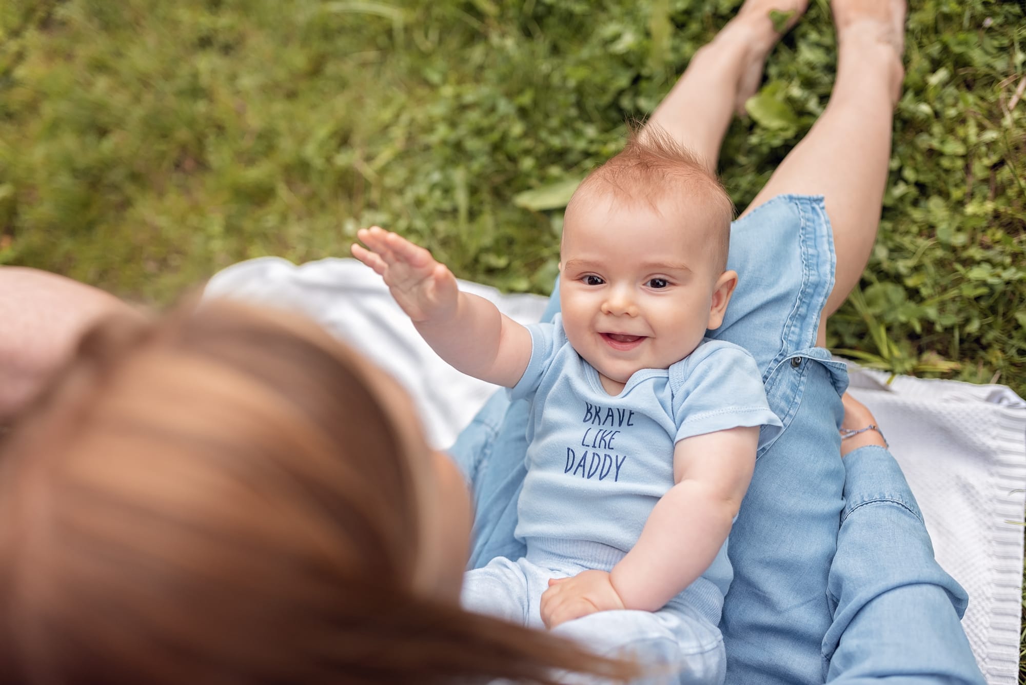 Niemowlak leży na kolanach u mamy sesja w parku Gdańsk