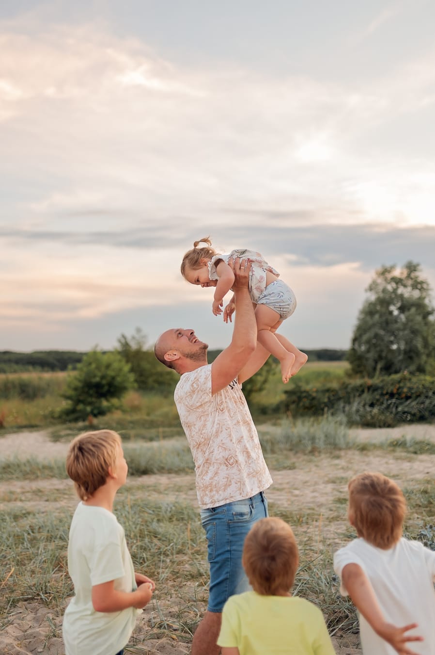 Tata podrzuca córkę sesja wielodzietna nad morzem