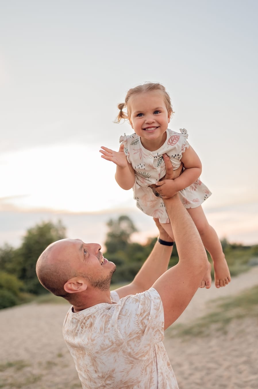 Tata podnosi córkę do góry sesja rodziny wielodzietnej plaża
