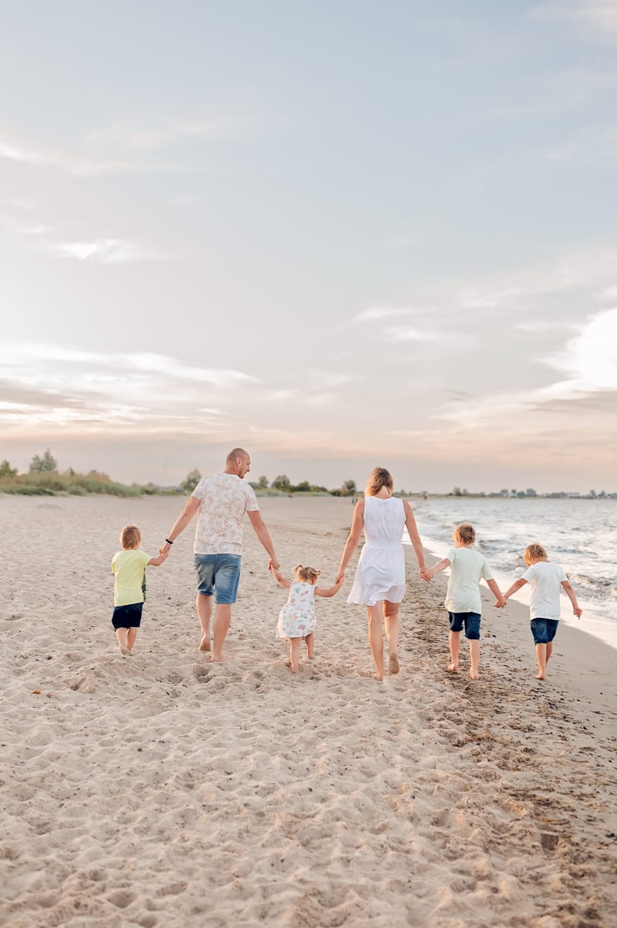 Rodzina wielodzietna idzie brzegiem morza zachód słońca