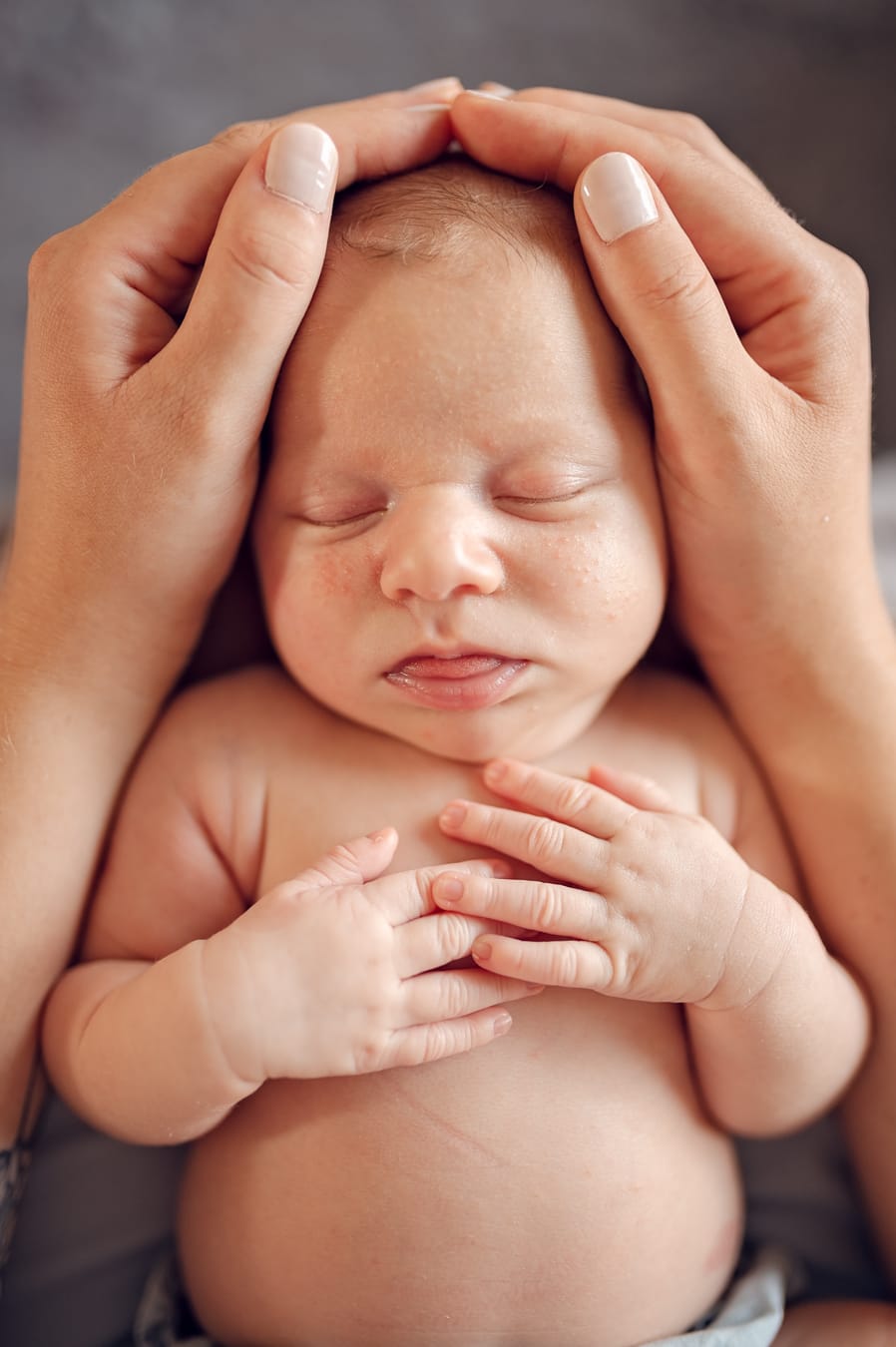 Noworodek w dłoniach mamy fotografia noworodkowa w domu