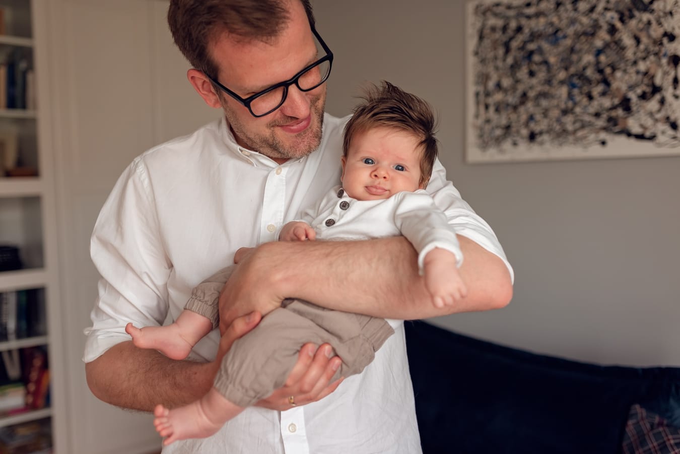 Niemowlę z bujną czupryną u taty sesja w domu