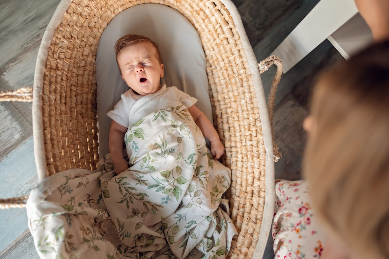 Niemowlę ziewa w koszu mojżesza sesja w domu