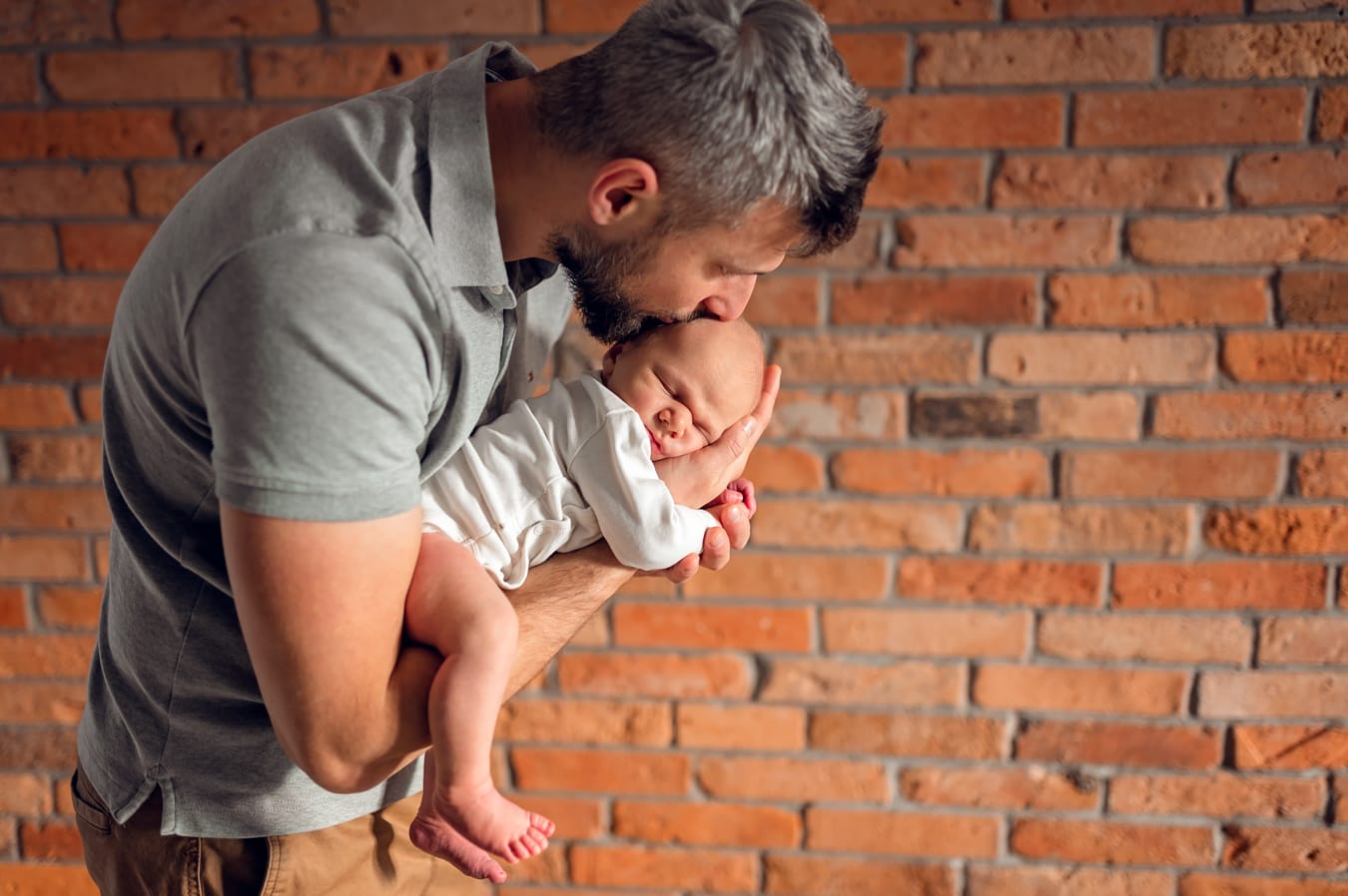 Tata całuje noworodka sesja noworodkowa Gdańsk