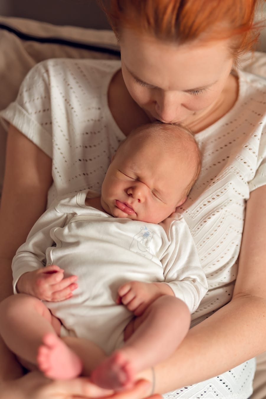 Mama całuje noworodka w czoło sesja w domu Gdańsk