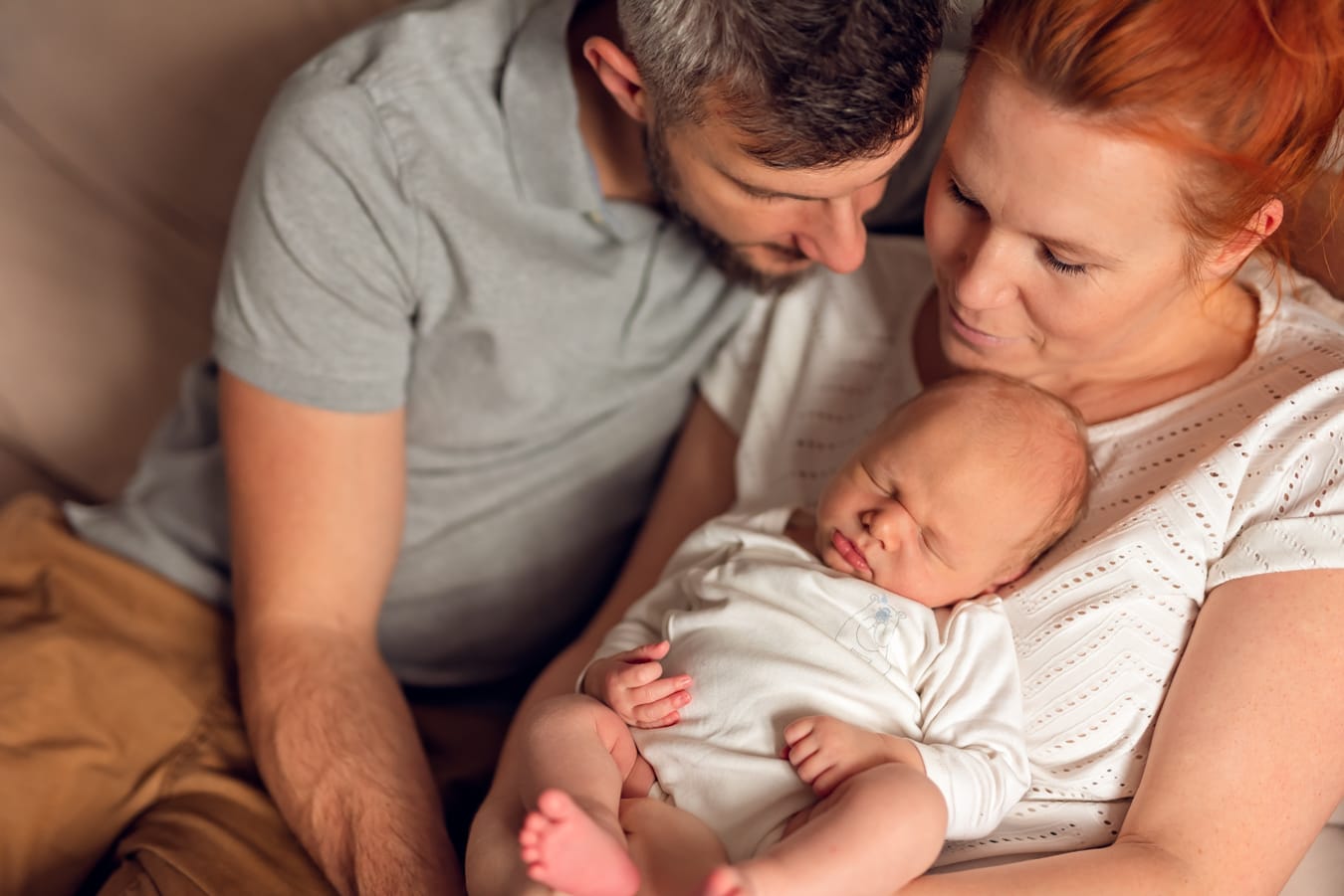 Rodzice patrzą na noworodka sesja w domu Gdańsk