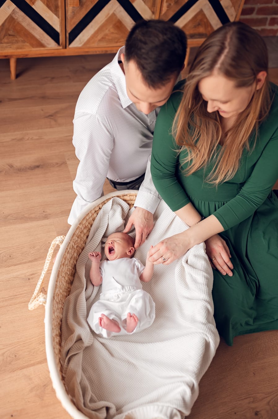Rodzice nad ziewającym noworodkiem sesja noworodkowa w domu