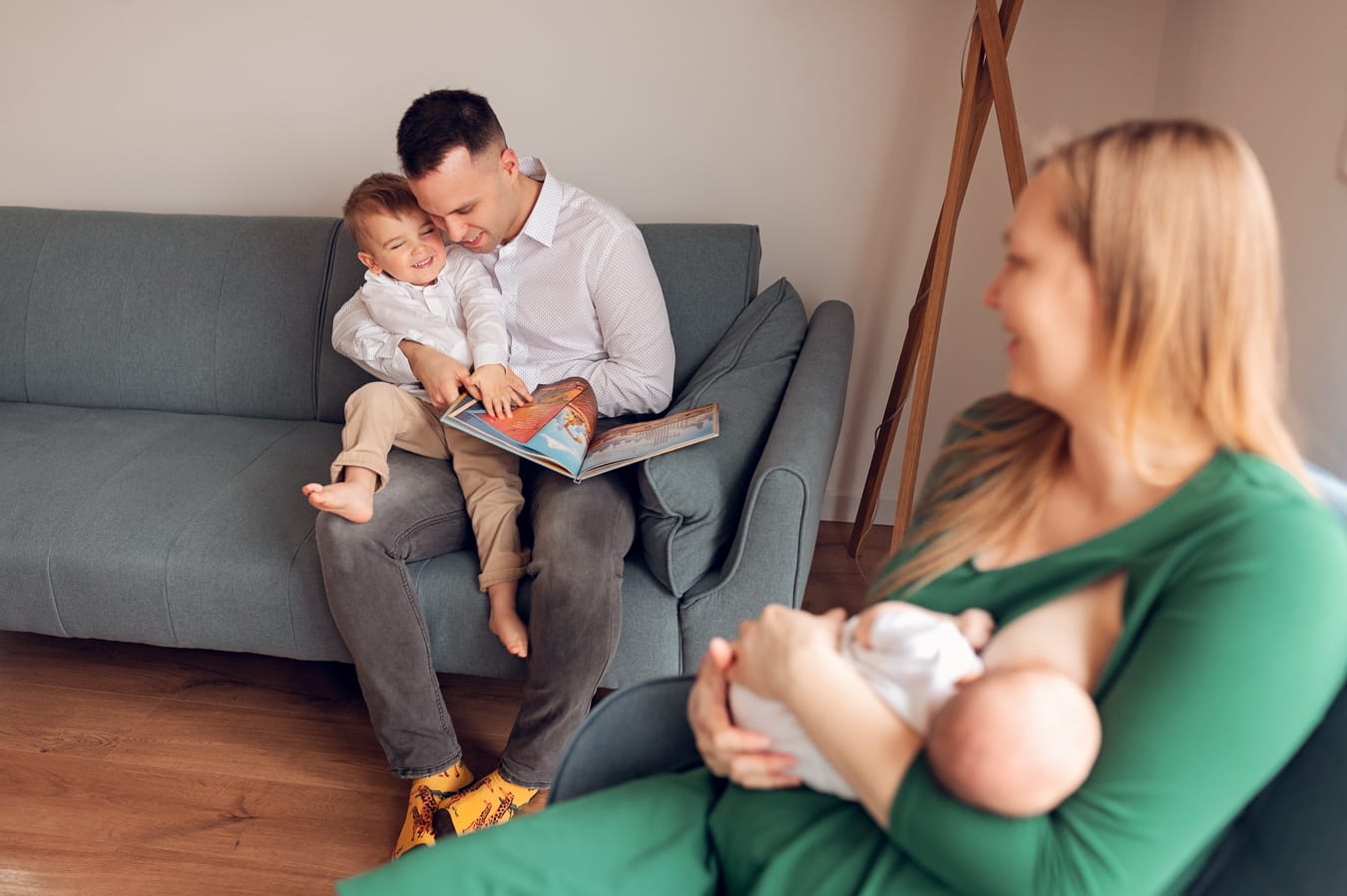 Tata czyta bajkę synowi mama karmi noworodka rodzinna sesja