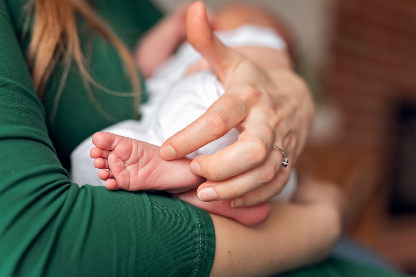 Mama głaszcze stópkę noworodka detal sesja w domu
