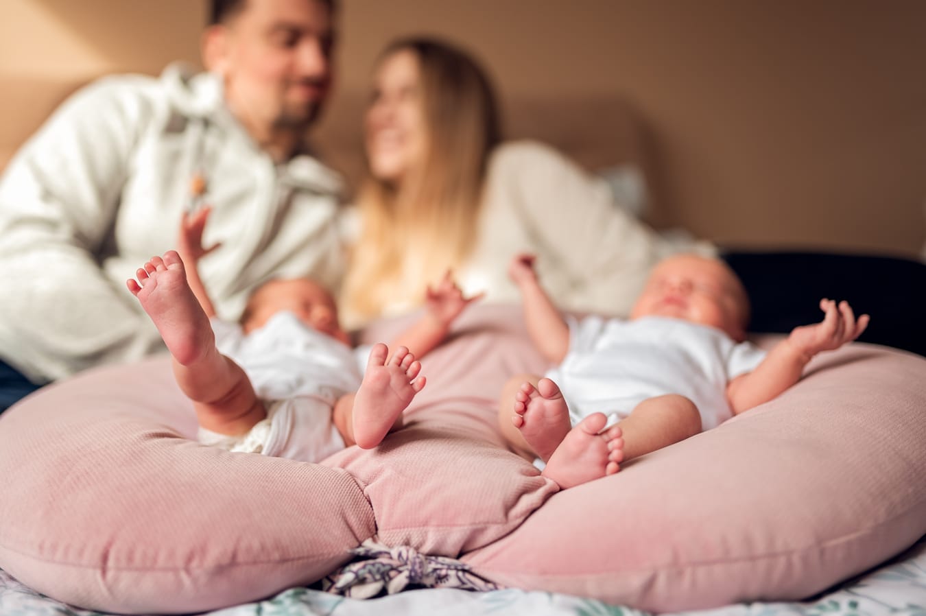 Detal stópek sióstr bliźniaczek a w tle uśmiechnięci rodzice sesja Gdynia