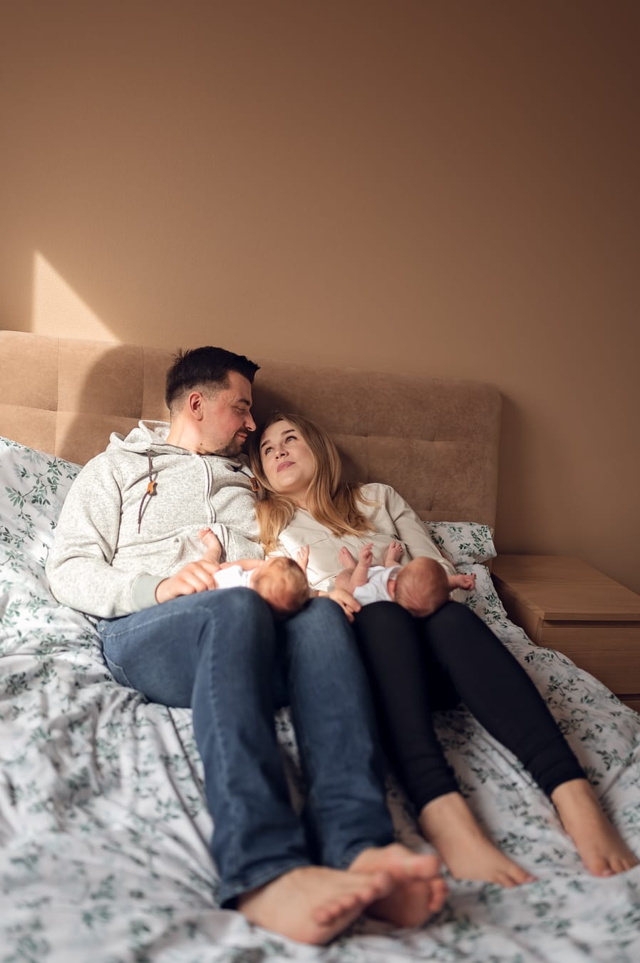 Rodzice trzymają bliźnięta na kolanach i przytulają się sesja noworodkowa lifestyle Gdynia