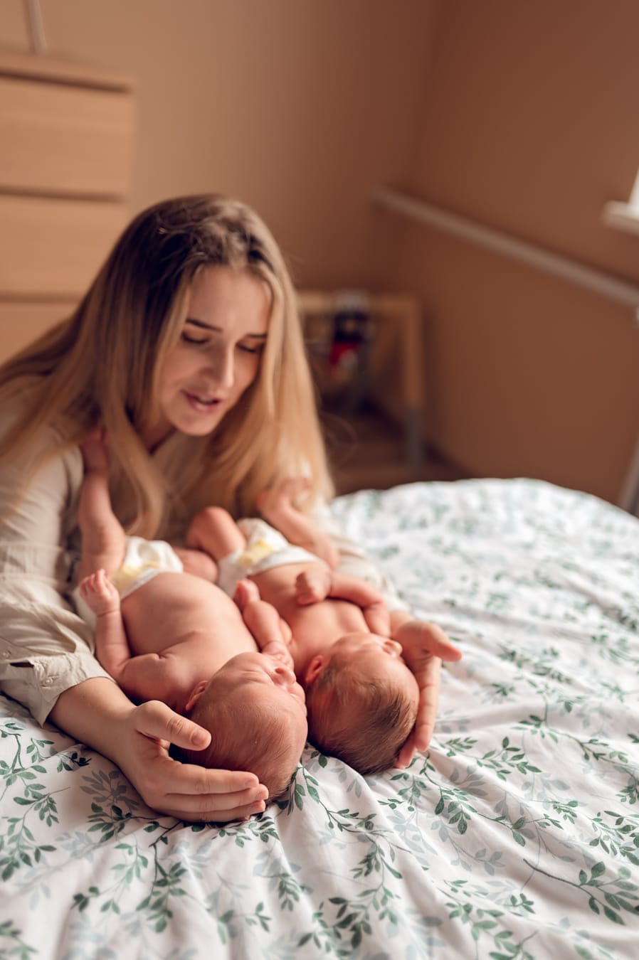 Bliźnięta w ramionach mamy sesja noworodkowa w domu