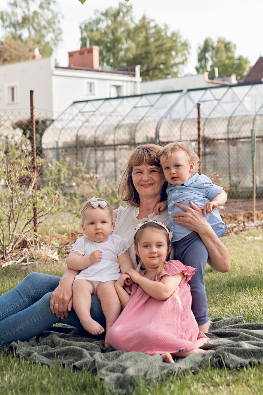 Sesja rodzinna w ogrodzie dziadków - babcia z wnukami podczas sesji wielopokoleniowej