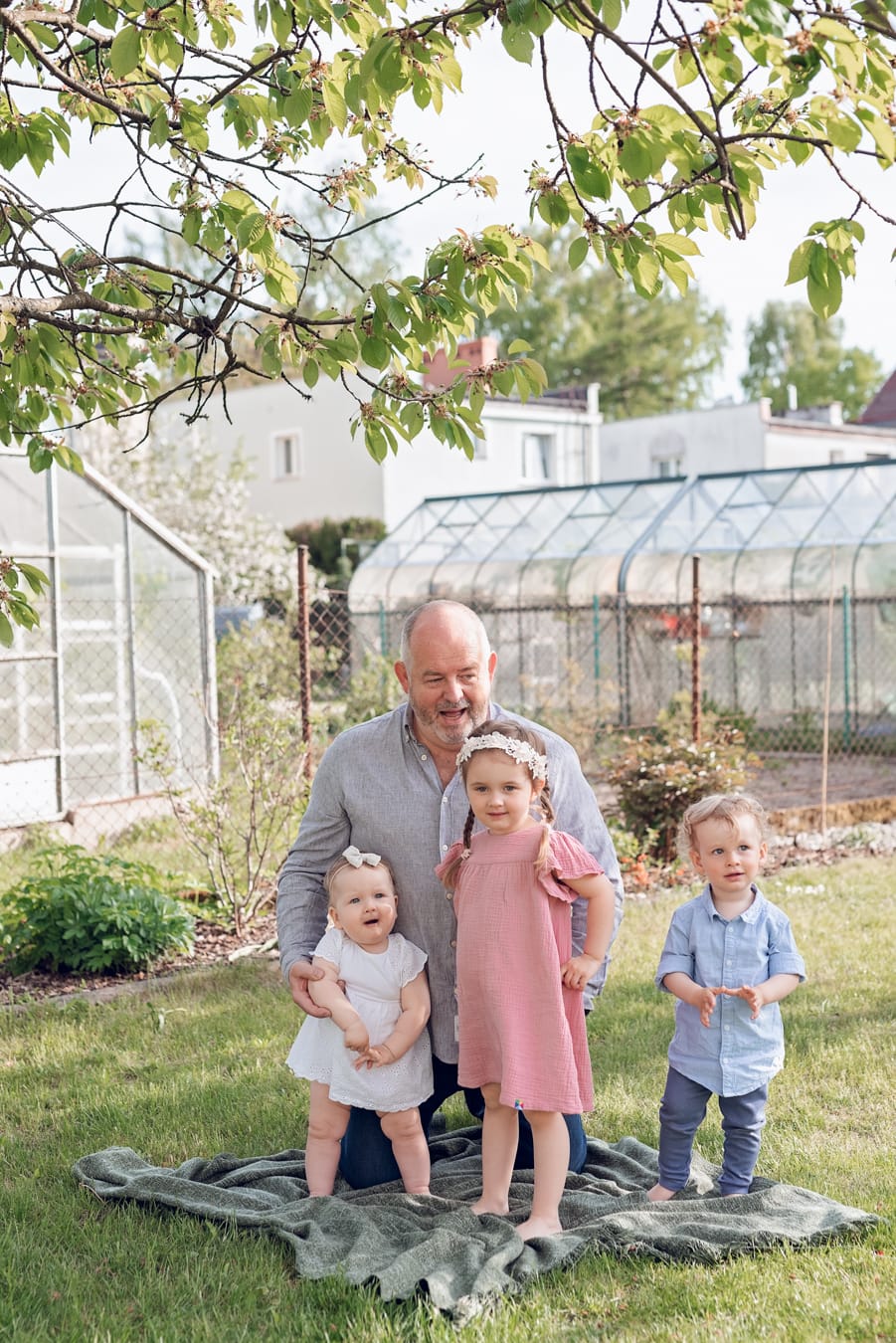 Sesja rodzinna w ogrodzie dziadków - dziadek z wnukami podczas sesji wielopokoleniowej