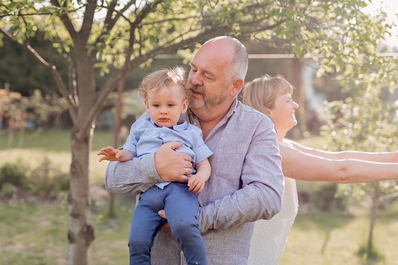 Ujęcie pełne uśmiechów i spontaniczności - wielopokoleniowa sesja rodzinna w ogrodzie dziadków