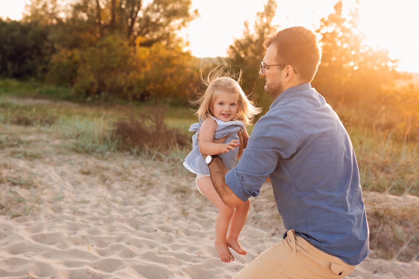 Tata trzyma córkę w złotym świetle sesja nad morzem