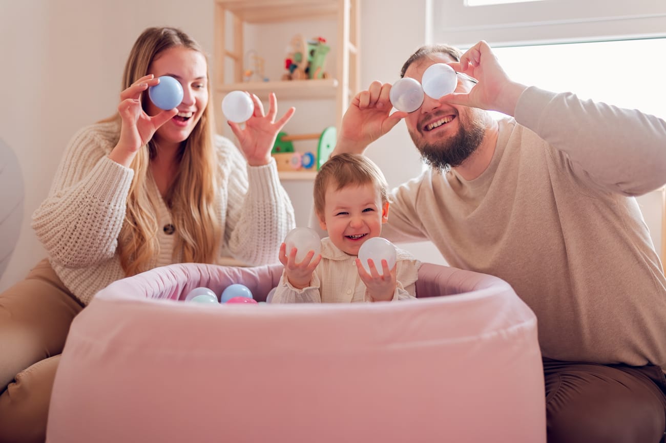Rodzina bawiaca się w dziecięcym pokoju piłeczkami w kulkowym basenie.