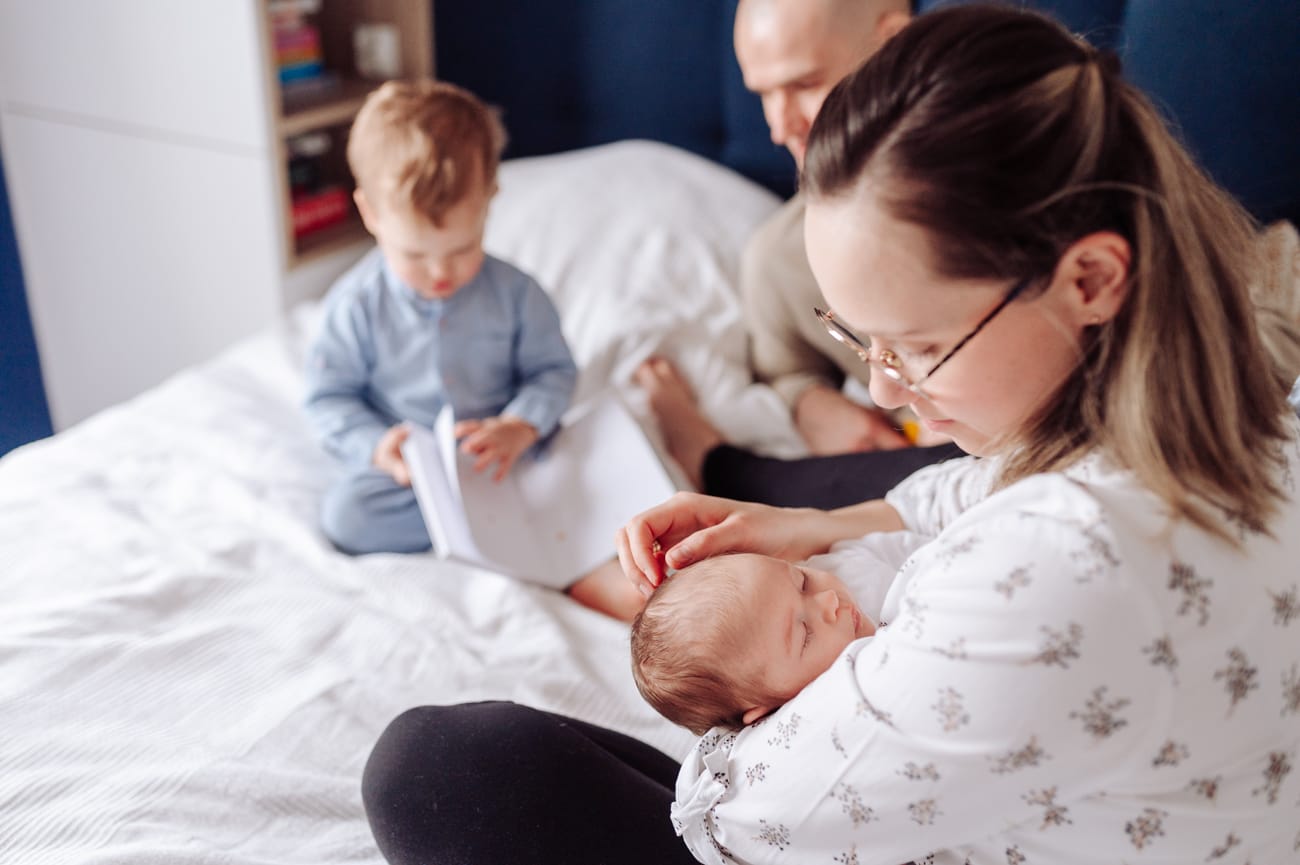 Mama głaszcze główkę noworodka sesja w domu
