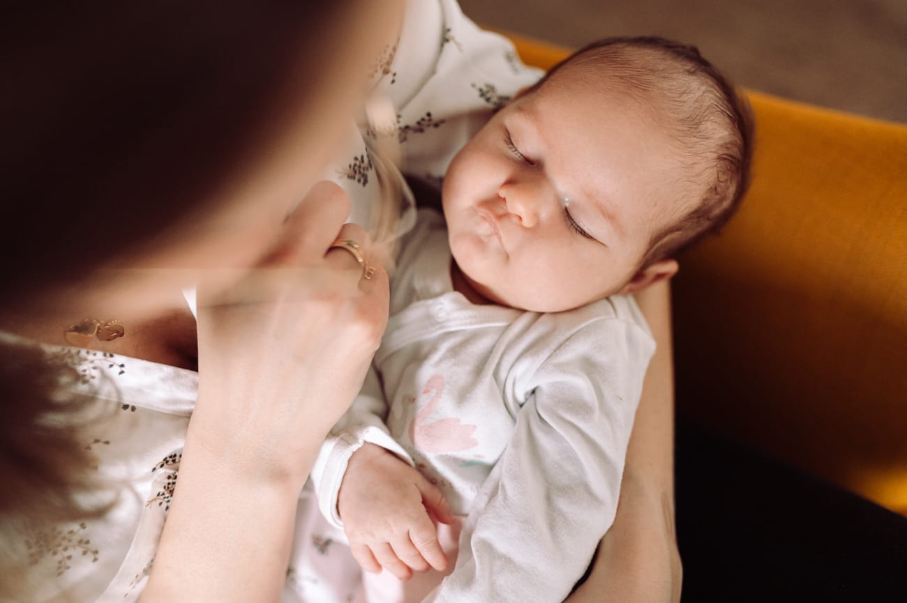 Noworodek śpi w ramionach mamy sesja w domu Gdynia