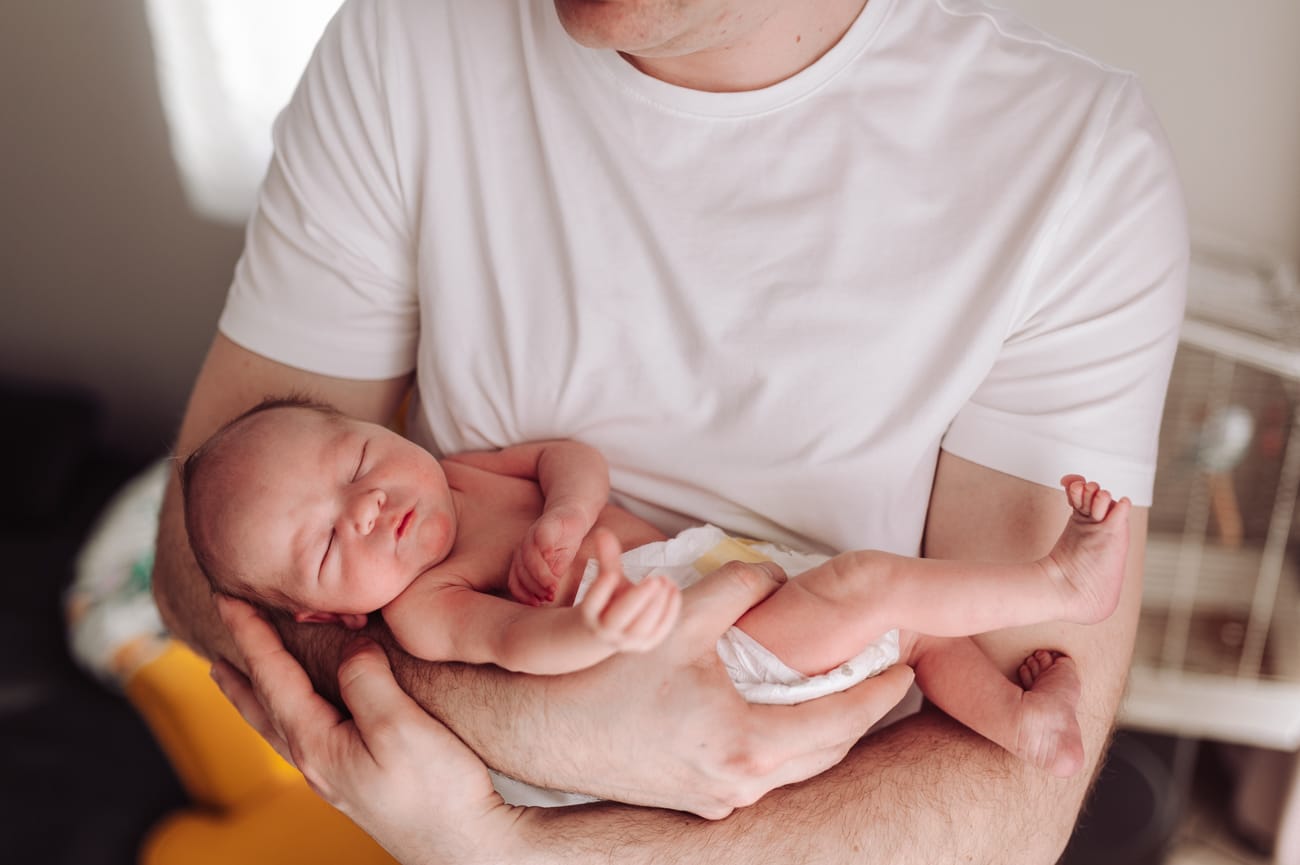 Śpiący noworodek na rękach taty jak wygląda sesja w domu Gdynia
