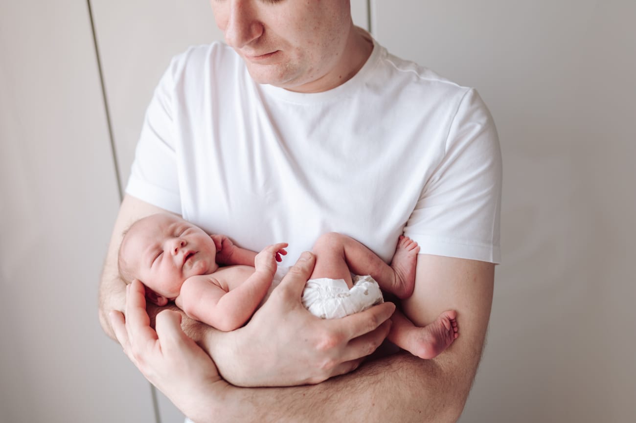 Noworodek w ramionach taty zbliżenie sesja w domu