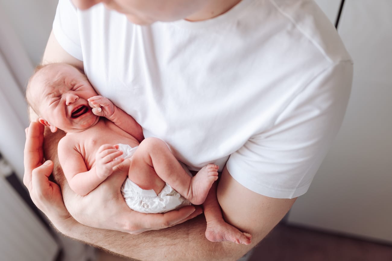 Płaczący noworodek w ramionach taty sesja w domu Gdynia
