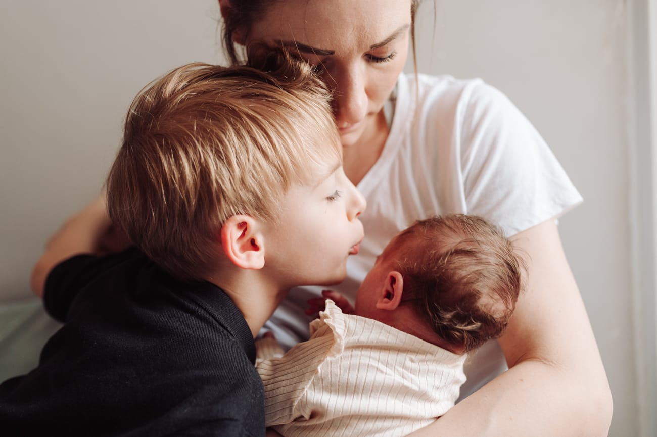 Starszy brat tuli noworodka sesja mama z dziećmi w domu